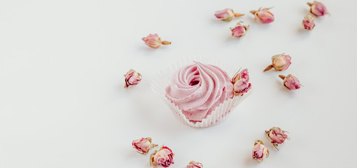 Pink fruit marshmallow and dried buds of roses on the white background. 
