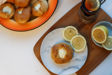 Cosy breakfast concept, transparent cup of tea with lemon and pastry on white background, near the window, flat lay