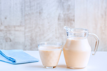 Fermented baked milk in a jug and in a glass on the table. Copy space.