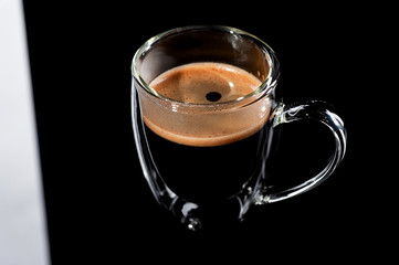 black coffee in a glass transparent cup on a black background