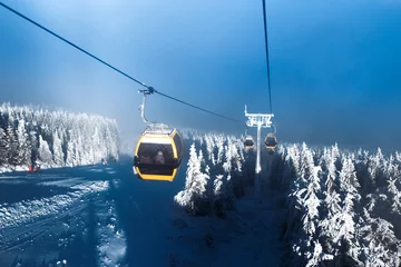 Tuinposter Gondolas rises in the mountains, ski resort, snow-covered Christmas trees, winter landscape © Vladyslav