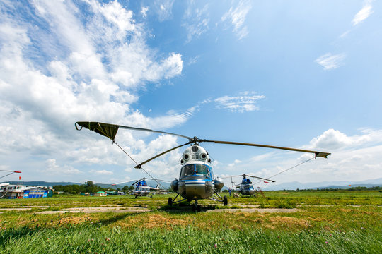 Novonezhino, Russia - Village airfield. Russian helicopter stands in a green field against the backdrop of a beautiful sky. - Powered by Adobe
