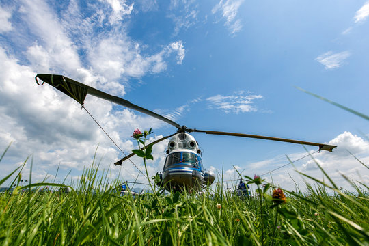 Novonezhino, Russia - Village airfield. Russian helicopter stands in a green field against the backdrop of a beautiful sky. - Powered by Adobe