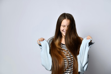 Teenager with long hair, in striped t-shirt and denim jacket. She is laughing, posing isolated on...