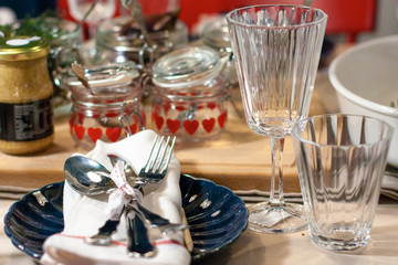 Festive table setting served for a person with two glass jars with hearts and dark blue shall shaped plate.