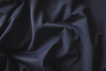 Folded dark blue woolen fabric textile close up for background. 