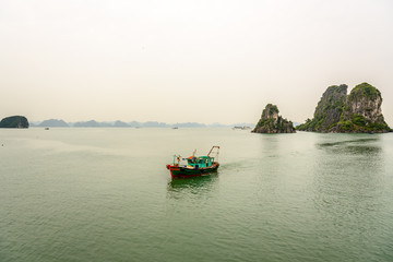 Fototapeta na wymiar Traditional Vietnamese Sailing Fishing Boat in Bai Tu Long Bay in Halong Bay Vietnam on a Cloudy Day