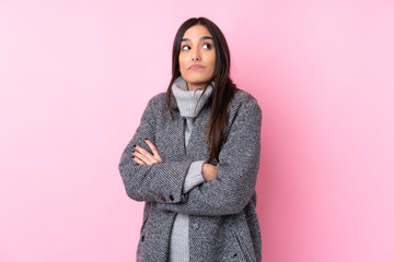 Young brunette woman over isolated pink background making doubts gesture while lifting the shoulders