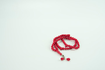 Red tasbih or rosary beads over white background.