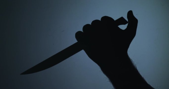 The shape of a hand with a knife on blue background ready to kill someone 