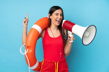 Lifeguard woman over isolated blue background with lifeguard equipment and shouting through a megaphone - obrazy, fototapety, plakaty