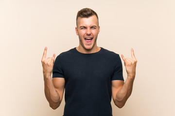 Fototapeta premium Young handsome blonde man over isolated background making rock gesture