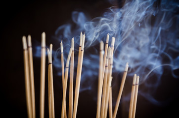 Incense sticks and smoke are burning in incense pot
