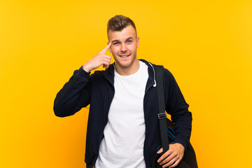 Young blonde sport man over isolated yellow background intending to realizes the solution