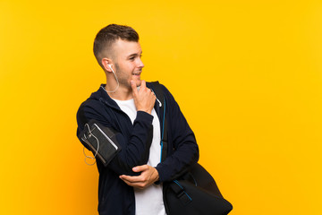 Young blonde sport man over isolated yellow background looking side