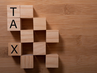 Tax with wooden alphabet blocks, on plank wooden background with copy space