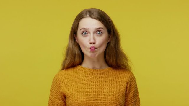 Humorous funny beautiful girl in pullover laughing, making fish face with pout lips and showing comical goofy grimace, carefree childish behavior. indoor studio shot isolated on yellow background