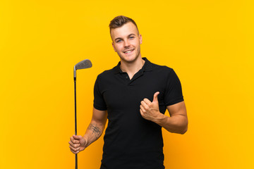 Golfer player man over isolated yellow background with thumbs up because something good has happened