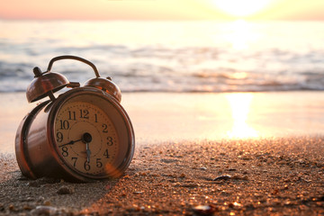 Morning of a new day, alarm clock on the beach sunlight in morning. Health and holiday concept.