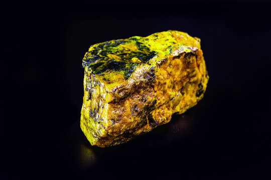 uranium mineral isolated on black background. Highly radioactive and dangerous ore.
