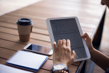 Women's hands with neat manicure and large wristwatch, work with gadgets, tablet, smartphone, papers on a wooden table.