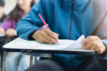 soft focus.high school,university student study.hands writing paper answer sheet.sitting lecture chair taking final exam attending in examination classroom.concept scholarship for education abroad