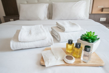 Set of hotel amenities (such as towels, shampoo, soap, gel etc) on the bed. Hotel amenities is something of a premium nature provided in addition to the room when renting a room. - obrazy, fototapety, plakaty