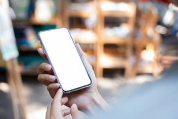 Mockup image blank white screen cell phone.men hand holding texting using mobile walking in market.background empty space for advertise text.people contact marketing business and technology