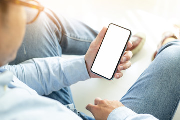 Mockup image blank white screen cell phone.men hand holding texting using mobile sitting on floor home.background empty space for advertise text.people contact marketing business and technology
