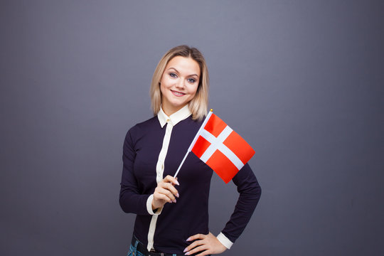 Immigration and the study of foreign languages, concept. A young smiling woman with a Denmark flag in her hand.