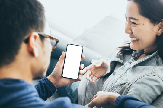 Mockup image blank white screen cell phone.couple lover holding texting using mobile on sofa at home.background empty space for advertise text.people contact marketing business and technology