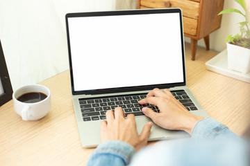 Fototapeta premium mockup image blank screen computer with blank white background for advertising text,hand man using laptop contact business search information on desk at home office.marketing and creative design