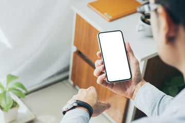 Mockup image blank white screen cell phone.man hand holding texting using mobile on desk at home office.background empty space for advertise text.people contact marketing business,technology