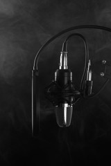 Professional microphone in a recording studio. Black and white photo. Black background, vertical frame.