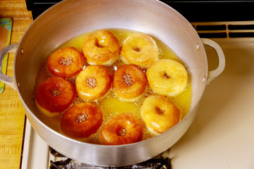Frying donuts with hole in hot oil in deep pan.