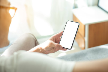 Mockup image blank white screen cell phone.man hand holding texting using mobile on sofa at home office.background empty space for advertise text.people contact marketing business,technology