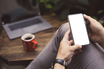 Mockup image blank white screen cell phone.man hand holding texting using mobile on desk at home office.background empty space for advertise text.people contact marketing business,technology