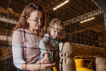 Mom and daughter enthusiastically shoot with a toy gun in the children's entertainment center