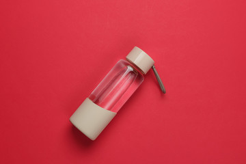 Bottle of water for sports and outdoor activities on red background. Top view