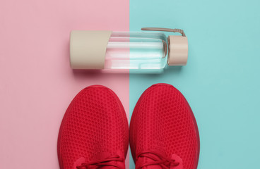 Flat lay style concept of healthy lifestyle, sport and fitness. Sports shoes for running,  bottle of water on pink blue pastel background. Top view