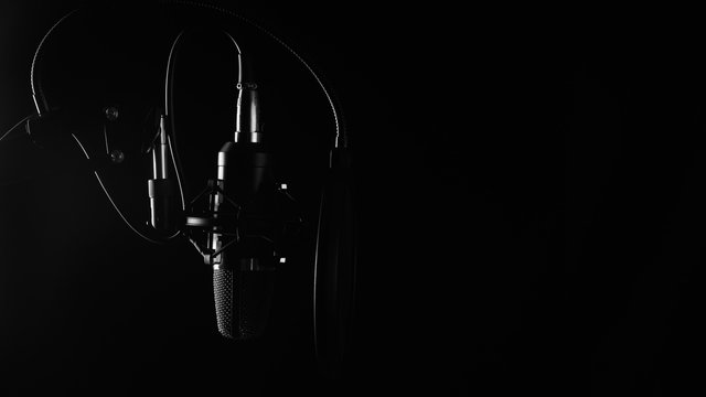 Professional microphone in a recording studio. Black and white photo. Black background, with space.