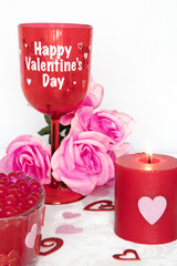 Valentines Day still life with red glass, candle, and pink roses. Romantic Concept on white soft background.