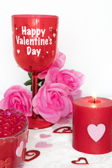 Valentines Day still life with red glass, candle, and pink roses. Romantic Concept on white soft background.