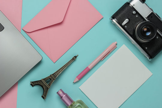 Envelope with letter, retro camera, laptop and beauty accessories on pink blue pastel background. Top view. Travel concept. Flat lay