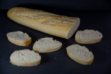 Barra de pan con rebanadas cortadas sobre una bandeja negra de piedra