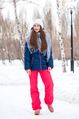 Portrait of a young beautiful woman in a ski suit posing in winter park