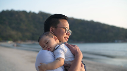 Holiday concept. Parents lull the baby to sleep on the beach. 4k Resolution.