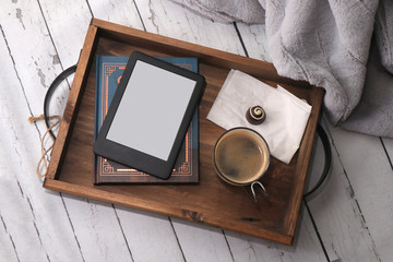rustic wooden tray with a book, a blank ebook coffee and chocolate on white birch table
