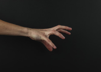 Female hand reaches for something on a black background