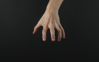 Female hand reaches for something on a black background